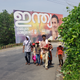 A Christian family walks past a billboard depicting Rahul Gandhi during the Good Friday Via Crucis procession.